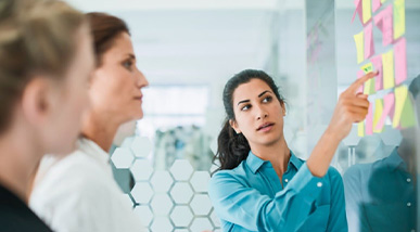 3 woment attentively looking at board covered in post it